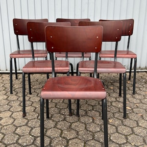 May include: Six vintage wooden chairs with black metal legs. The chairs have a dark brown wood finish and are arranged in a row.