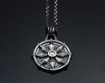 May include: A silver chain necklace with a round pendant featuring a silver and bronze design with a clear crystal in the centre.