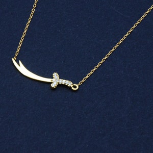 May include: A gold chain necklace with a small, diamond-encrusted sword pendant.