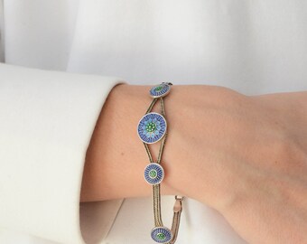 Puede incluir: Un brazalete de oro con círculos de esmalte azul y verde. El brazalete tiene un diseño de cadena delicado.
