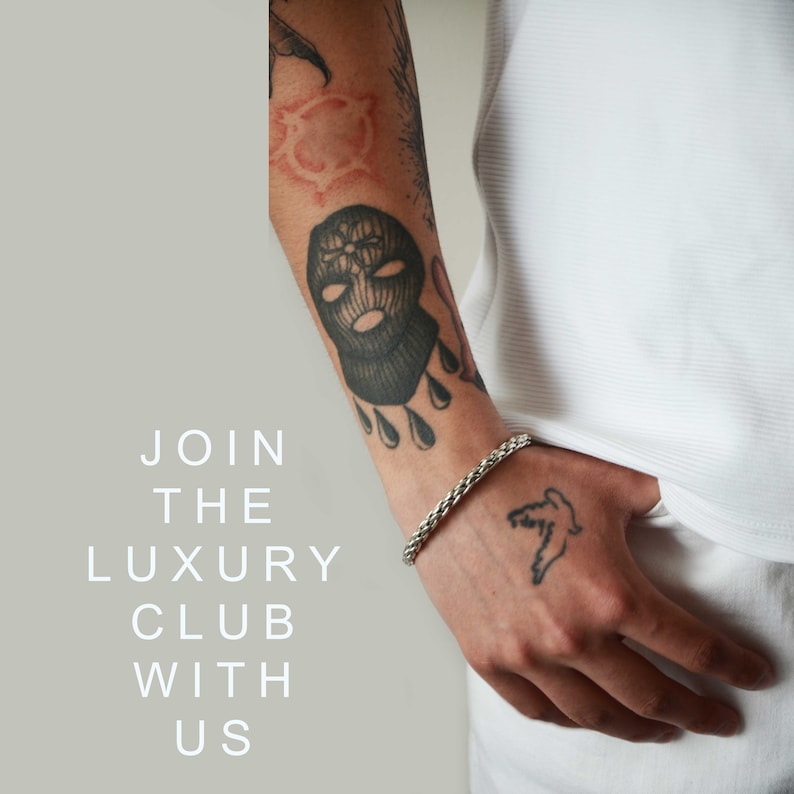 May include: A person wearing a white shirt with a silver chain bracelet on their wrist. The person has a black and white tattoo of a ski mask on their arm and a bird tattoo on their hand. The text "JOIN THE LUXURY CLUB WITH US" is written in white on a gray background.