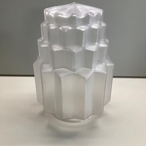 Puede incluir: Pantalla de lámpara de vidrio transparente esmerilado con un diseño geométrico escalonado. La pantalla tiene una parte superior en forma de estrella y una serie de niveles octogonales, creando una estética vintage art déco. Adecuado para lámpara de mesa o techo.