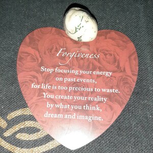 May include: A heart-shaped card with a red background and white text that reads "Forgiveness". The text continues with "Stop focusing your energy on past events, for life is too precious to waste. You create your reality by what you think, dream and imagine."