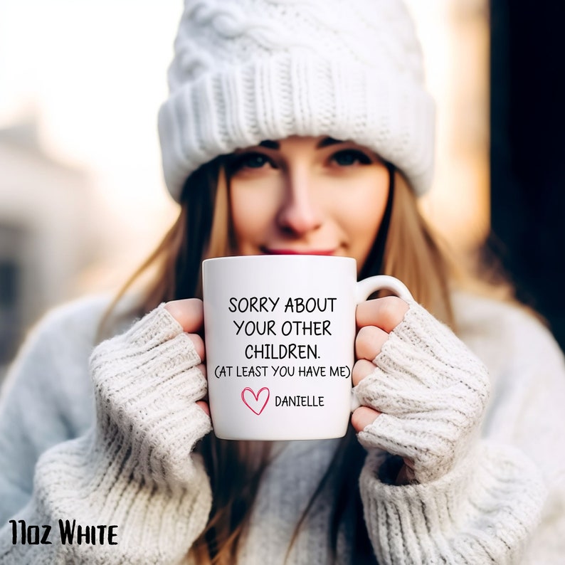 May include: White ceramic mug with black text that reads "Sorry about your other children. (At least you have me)" and a pink heart with the name "Danielle" below.