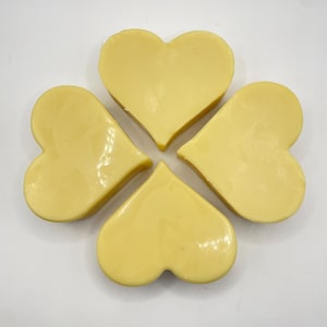 May include: Four heart-shaped objects arranged like a four-leaf clover. The objects are a pale yellow colour and appear to be solid. The background is plain white.