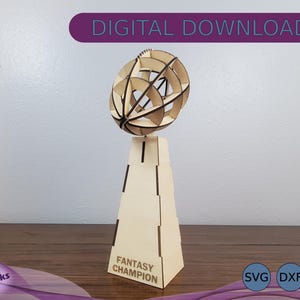 May include: A wooden trophy with a geometric sphere on top. The base of the trophy is a rectangular prism with the words "Fantasy Champion" inscribed on the front. The trophy is made of light brown wood and has a natural finish.