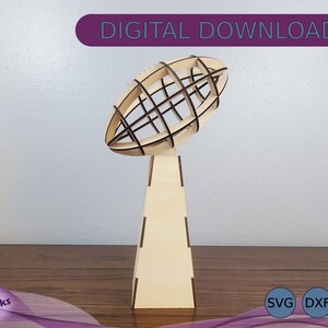 May include: A wooden trophy shaped like a football with a lattice design. The trophy is on a wooden base. The base is a square shape with a pointed top. The trophy is a digital download and comes in SVG, DXF, and EPS formats.