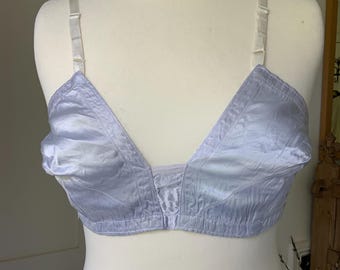 Könnte beinhalten: Ein hellblauer BH mit verstellbaren Trägern. Der BH wird auf einer Schaufensterpuppe präsentiert. Er hat ein satinartiges Aussehen und ein klassisches Design. Die Träger sind hell und neutral.