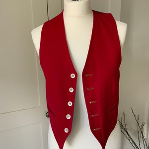 K&ouml;nnte beinhalten: Eine rote Wollweste mit spitzem Kragen und Knopfleiste. Die Weste hat sechs Kn&ouml;pfe und zwei Taschen.