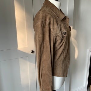 K&ouml;nnte beinhalten: Eine braune Wildlederjacke mit Knopfleiste und einer einzigen Patte auf der Brust.