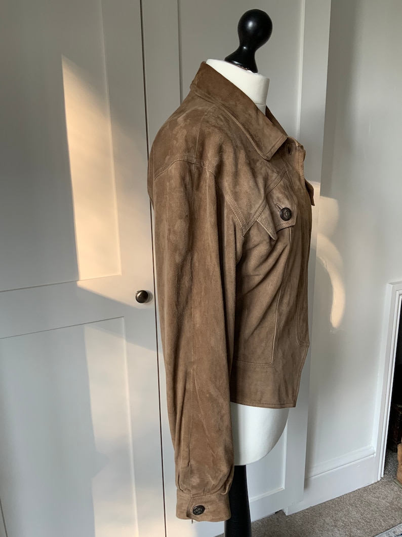K&ouml;nnte beinhalten: Eine braune Wildlederjacke mit Knopfleiste und einer einzigen Patte auf der Brust.