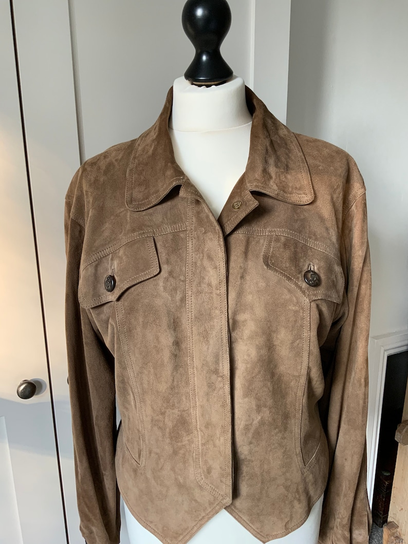 K&ouml;nnte beinhalten: Eine braune Wildlederjacke mit Knopfleiste und zwei Pattentaschen.