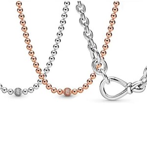 May include: Three silver necklaces with different chain styles. One necklace has a round, pave-set charm. Another necklace has a round, pave-set charm. The third necklace has a knotted, open-loop charm.