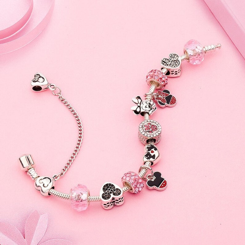 Pu&ograve; includere: Un braccialetto con ciondoli in argento con ciondoli rosa e neri con i personaggi di Topolino e Minnie Mouse. I ciondoli sono decorati con strass.