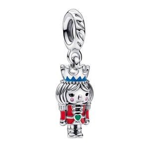 May include: Silver charm featuring a nutcracker doll with a blue crown, red and green clothing, and a green heart on the chest.