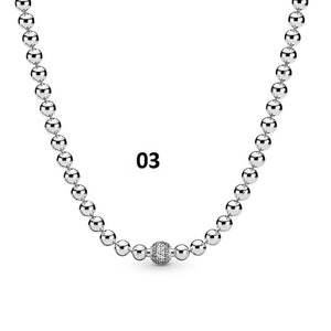 May include: A silver necklace with a round, sparkly charm in the center. The necklace is made of small, round beads.