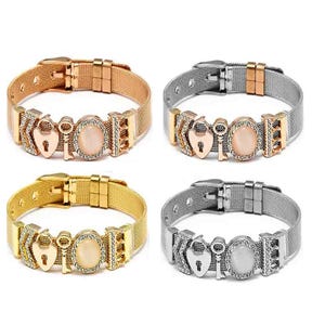 May include: Four mesh bracelets with buckle closures, each featuring a heart-shaped charm, a key charm, and an oval cabochon stone. The bracelets are available in rose gold, silver with rose gold accents, gold, and silver tones with clear crystals.