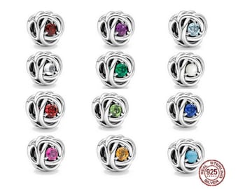 May include: Twelve silver charm beads with different coloured gemstones in the centre. Each bead is a knot design. The beads are arranged in three rows of four.