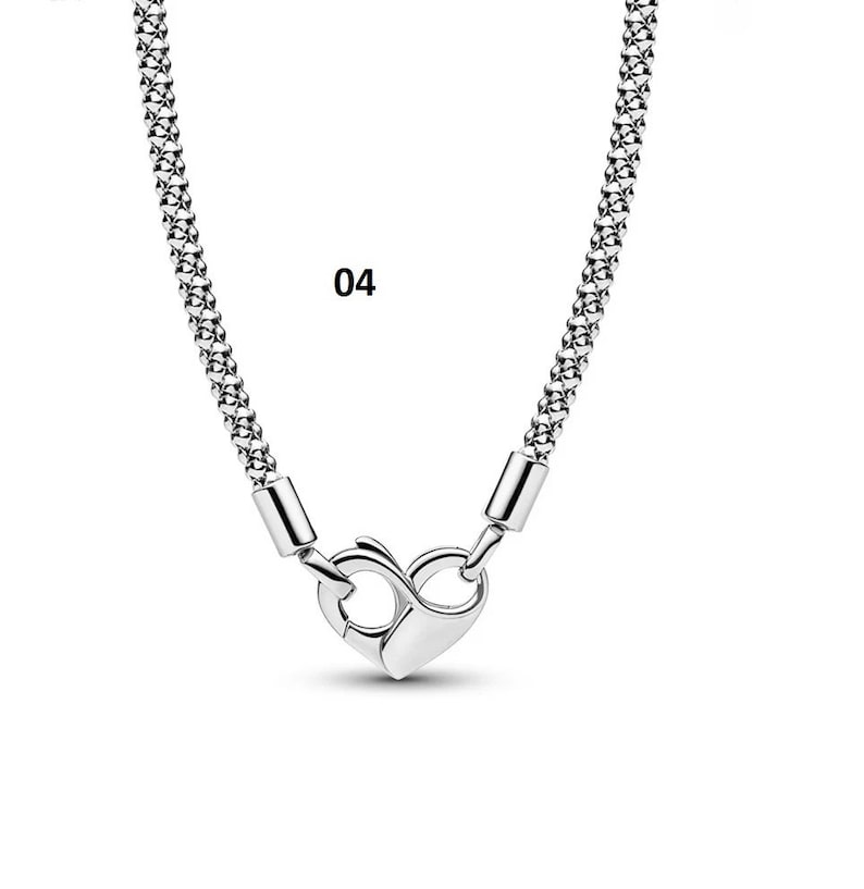 May include: A silver chain necklace with a heart-shaped clasp. The chain is made of small, linked circles.