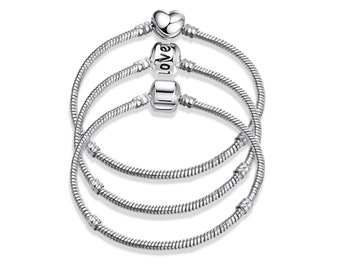 Pode incluir: Três pulseiras de corrente de cobra em tom prateado dispostas numa pilha. A pulseira superior apresenta um pendente em forma de coração, a do meio tem uma conta com a palavra LOVE gravada e a inferior inclui uma conta quadrada lisa.