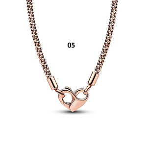 May include: A rose gold chain necklace with a heart-shaped clasp. The chain is made of small, linked squares. The number "05" is visible in the image.