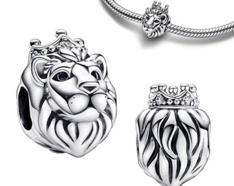 May include: Silver charm featuring a lion's head with a crown and sparkling stones. The charm is designed to be used on a bracelet or necklace.