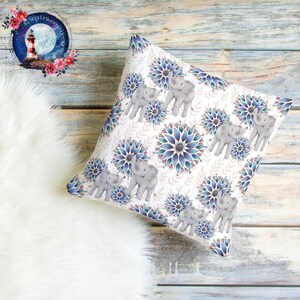 May include: A white throw pillow with a repeating pattern of blue and purple mandala-like flowers and gray elephants. The elephants are in pairs and are facing each other.