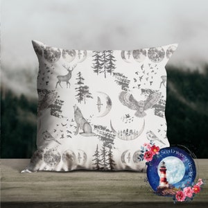 May include: A white throw pillow with a repeating pattern of gray watercolor illustrations of a wolf, deer, owl, trees, and crescent moons. The pillow is on a wooden surface. The text "Sea Universe Designs" is visible in the lower right corner of the image.