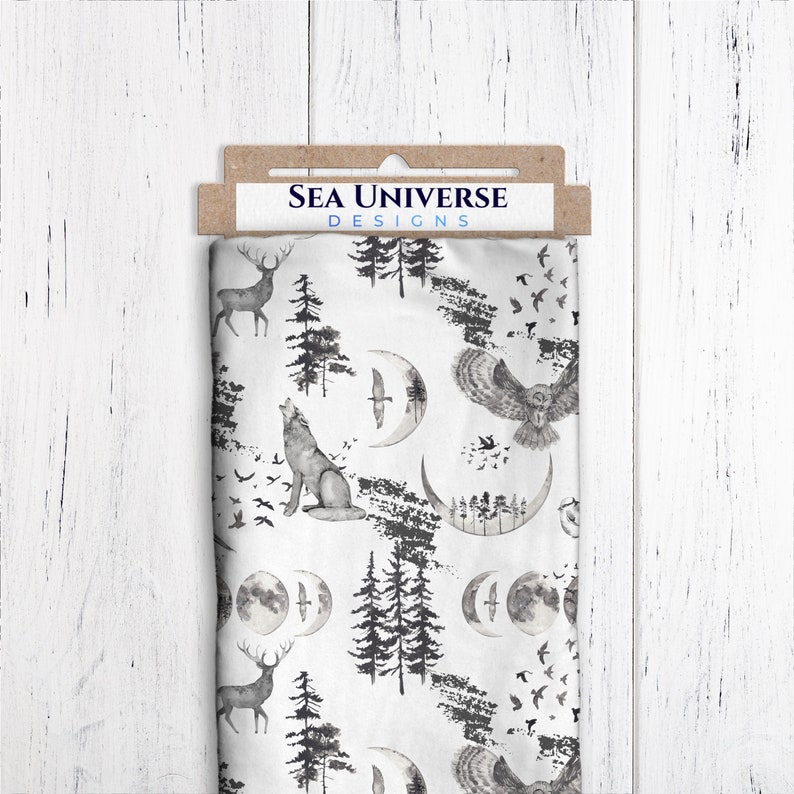 May include: White fabric with a black and gray print of a wolf howling at the moon, a deer, an owl, and trees. The fabric has the text "SEA UNIVERSE DESIGNS" printed on a brown tag.