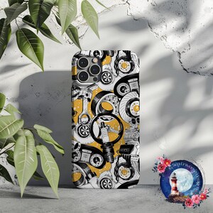 May include: A black and white phone case with a yellow background. The case features a pattern of car parts, including pistons, gears, and spark plugs.