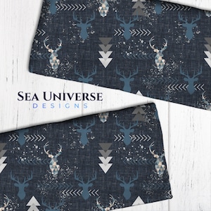 以下が含まれることがあります： 白い幾何学模様と青い鹿のシルエットが繰り返しパターンになっている紺色の生地。生地は、リネンに似た質感があり、白い飛び散った塗料の効果があります。画像には「SEA UNIVERSE DESIGNS」というテキストが表示されています。