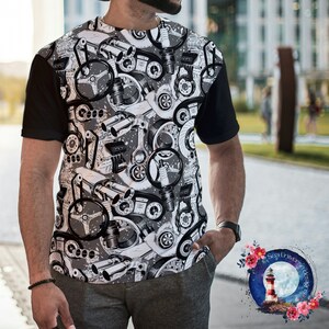May include: A black and white t-shirt with a graphic print of various car engine parts. The shirt has a black collar and short sleeves.