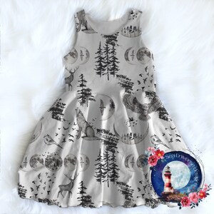 May include: A gray sleeveless dress with a whimsical woodland print featuring deer, wolves, owls, birds, trees, and crescent moons. The dress has a full skirt and a white background.