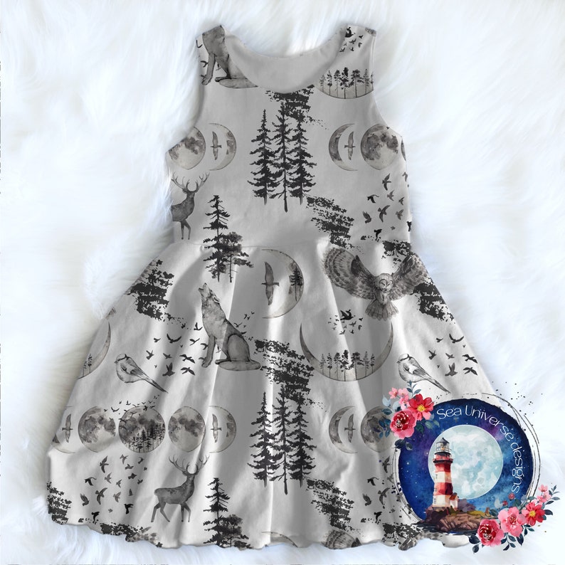 May include: A gray sleeveless dress with a whimsical woodland print featuring deer, wolves, owls, birds, trees, and crescent moons. The dress has a full skirt and a white background.