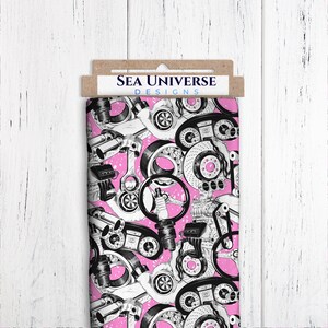 May include: Pink fabric with a black and white print of car engine parts. The fabric has the text "Sea Universe Designs" on a brown tag.