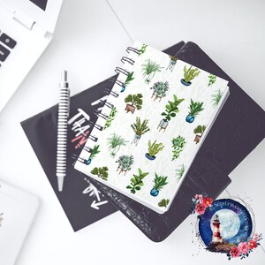 May include: A white spiral bound notebook with a repeating pattern of potted plants in various shades of green, brown, and blue. The plants are drawn in a watercolor style.