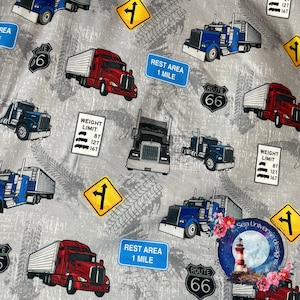 Può includere: Un tessuto grigio e bianco con un motivo ripetuto di camion, cartelli stradali e tracce di pneumatici. I camion sono blu e rossi con rimorchi bianchi. I cartelli includono "Route 66", "Area di sosta 1 miglio" e "Limite di peso 8T 12T 16T".
