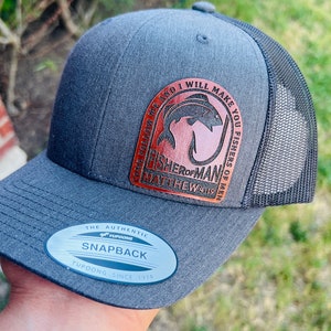 May include: A gray and black baseball cap with a brown leather patch that says "Come follow me and I will make you fishers of men" and "Fisher of Man Matthew 4:19". The cap has a mesh back and a YUPOONG SNAPBACK label.