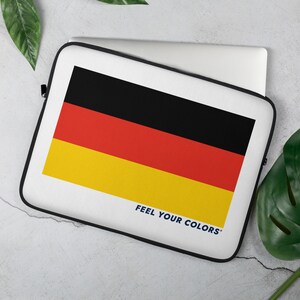 May include: A white laptop sleeve with a black, red, and yellow German flag design. The text "FEEL YOUR COLORS" is printed in blue at the bottom of the sleeve.