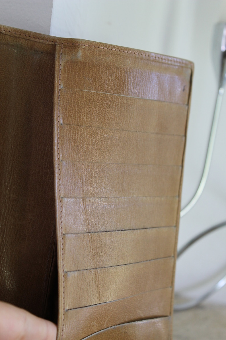 K&ouml;nnte beinhalten: Eine braune Ledergeldb&ouml;rse mit mehreren Kartenf&auml;chern und einem Klappverschluss.