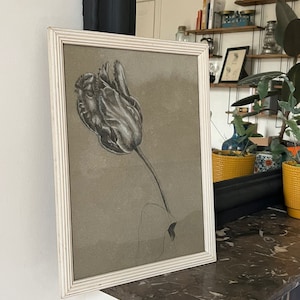 Puede incluir: Un dibujo enmarcado en blanco y negro de un solo tulipán con una hoja verde sobre un fondo beige.