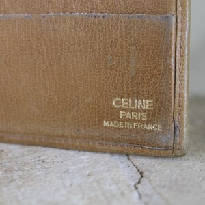 K&ouml;nnte beinhalten: Eine braune Ledergeldb&ouml;rse mit goldener Aufschrift "CELINE PARIS MADE IN FRANCE".