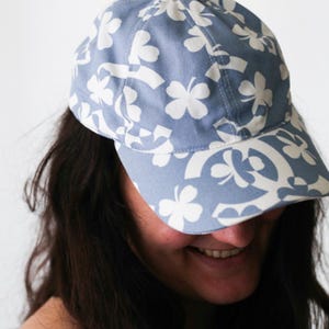 Può includere: Cappellino da baseball azzurro con motivo floreale bianco. Il cappellino ha una visiera curva e un design a sei pannelli. Il cappello è realizzato in tessuto morbido ed è adatto per l'abbigliamento casual.