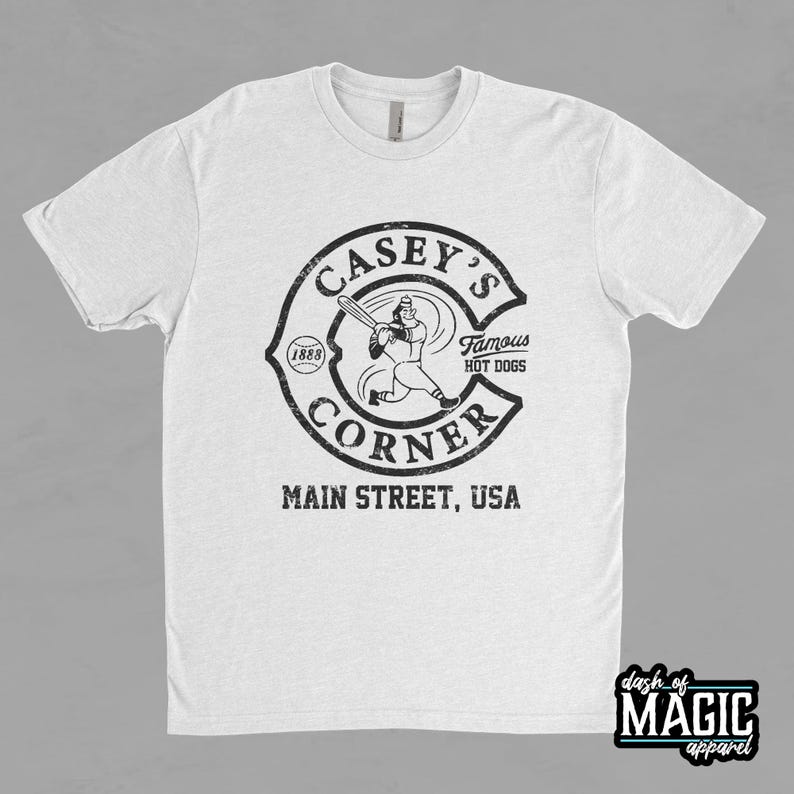 K&ouml;nnte beinhalten: Wei&szlig;es T-Shirt mit einer schwarz-wei&szlig;en Grafik eines Baseballspielers und dem Text "Casey's Corner, Main Street, USA, Famous Hot Dogs, (1888)"