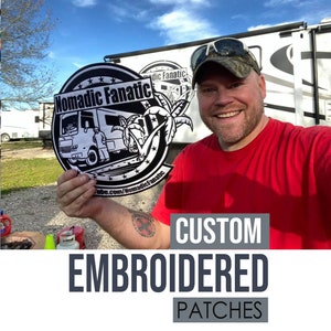 以下が含まれることがあります： 「Nomadic Fanatic」という文字と、レクリエーションビークルの漫画の絵が描かれた白黒の刺繍パッチ。赤いシャツと迷彩帽をかぶった人がパッチを持っています。画像の下には「CUSTOM EMBROIDERED PATCHES」という文字が表示されています。