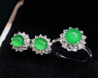 May include: A set of three jade rings with a green jade stone and a halo of small diamonds. The rings are set in silver.