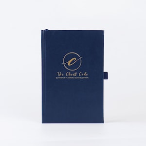 May include: A navy blue hardcover journal with a gold circle logo that says "The Cheat Code" and "Quarterly Planner & Guided Journal".