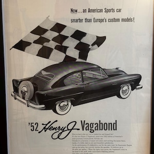 May include: An advertisement for the '52 Henry J Vagabond, an American sports car. The image features a black car with a spare tire, white-walled tires, and a checkered flag. Text reads "Now...an American Sports car smarter than Europe's custom models!"