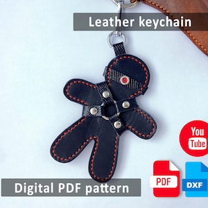 May include: Black leather keychain in a stylized human form with red stitching. The keychain has a harness design with silver-tone hardware. The text "Leather keychain" is above the keychain. The text "Digital PDF pattern" is below the keychain.