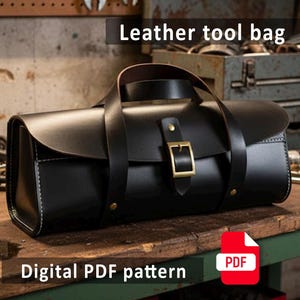 Puede incluir: Bolsa de herramientas de cuero negro con asa y cierre de hebilla. La bolsa tiene forma rectangular con bordes redondeados y costuras blancas. Se ve el texto "Leather tool bag" y "Digital PDF pattern".